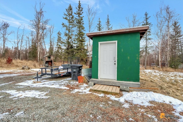 snow covered structure featuring a storage shed and an outbuilding