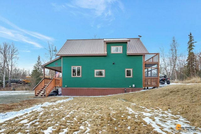 snow covered rear of property featuring metal roof