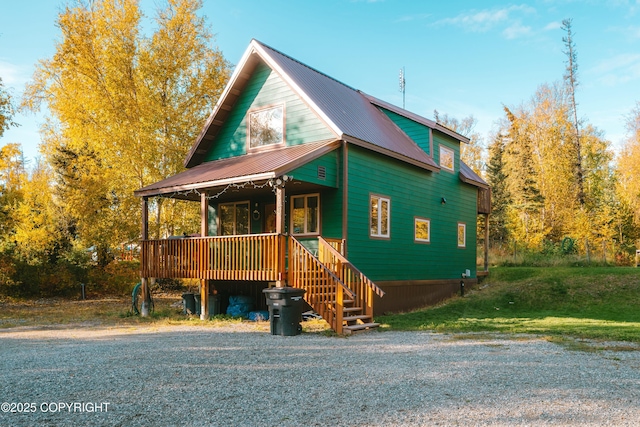 chalet / cabin featuring metal roof, covered porch, and a front lawn