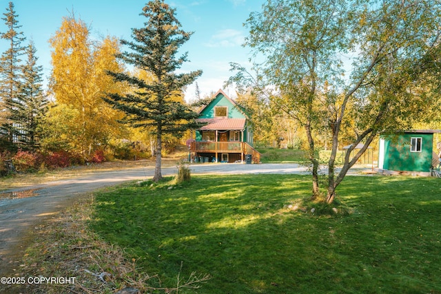 view of front of property with an outbuilding, a front lawn, dirt driveway, a storage shed, and metal roof