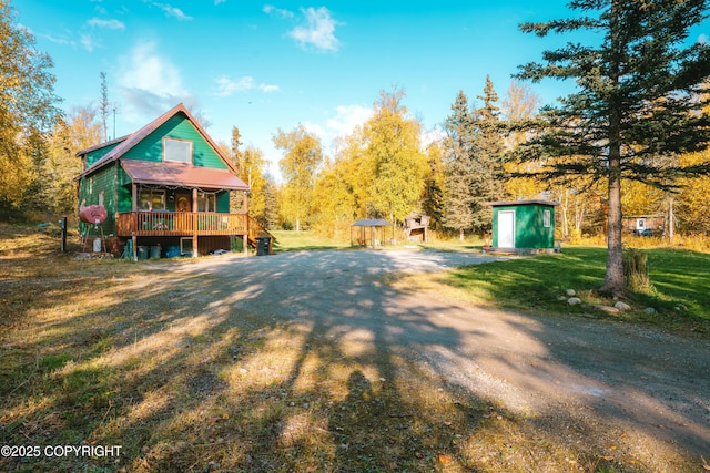 back of property with a porch, a yard, an outdoor structure, a storage unit, and metal roof