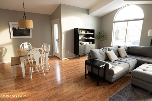 living area with vaulted ceiling, light wood-style flooring, and baseboards