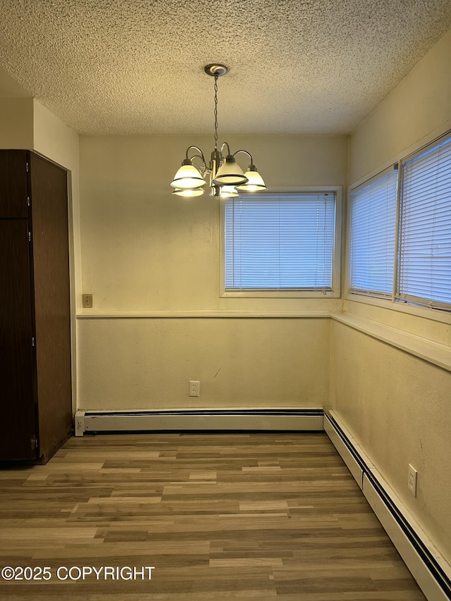 unfurnished dining area featuring a baseboard radiator, a notable chandelier, wood finished floors, and a textured ceiling