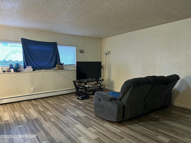 living room with a baseboard heating unit, wood finished floors, baseboards, and a textured ceiling