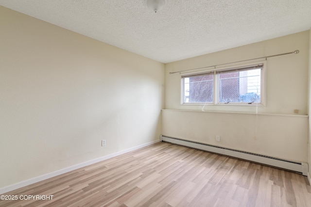 2752 W 42nd Ave Unit 4, Anchorage, AK 99517 - empty room featuring a baseboard heating unit, light wood-type flooring, baseboards, and a textured ceiling