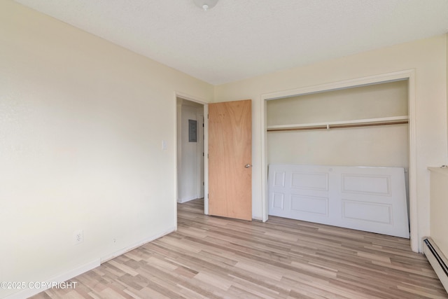 2752 W 42nd Ave Unit 4, Anchorage, AK 99517 - unfurnished bedroom with a baseboard radiator, light wood-type flooring, a closet, and baseboards
