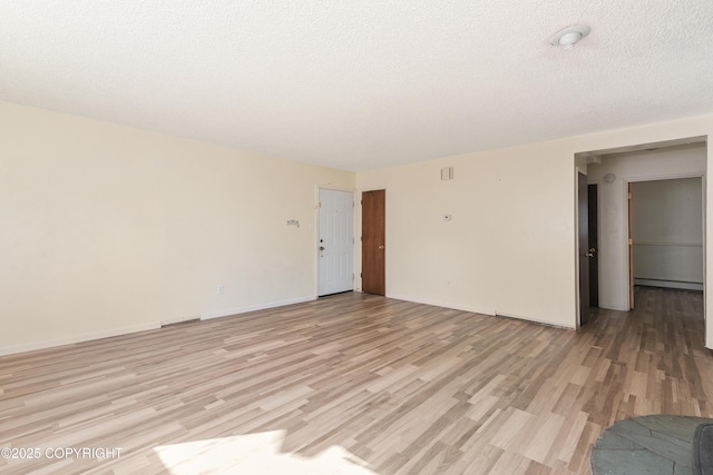 2752 W 42nd Ave Unit 4, Anchorage, AK 99517 - empty room with light wood-style floors, baseboard heating, baseboards, and a textured ceiling