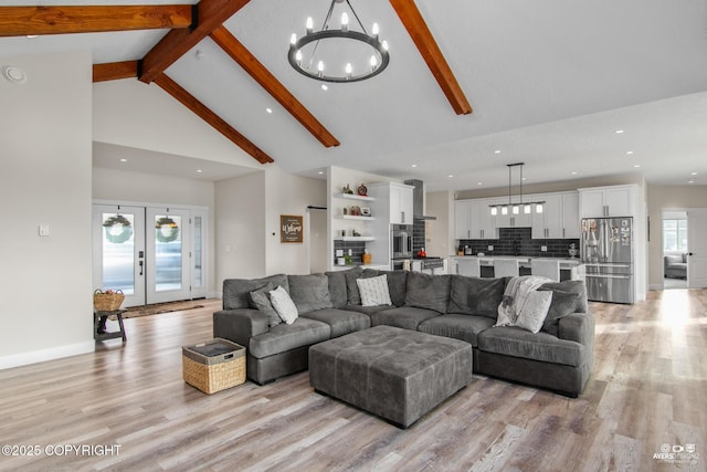 living area with baseboards, beam ceiling, light wood-style floors, an inviting chandelier, and high vaulted ceiling