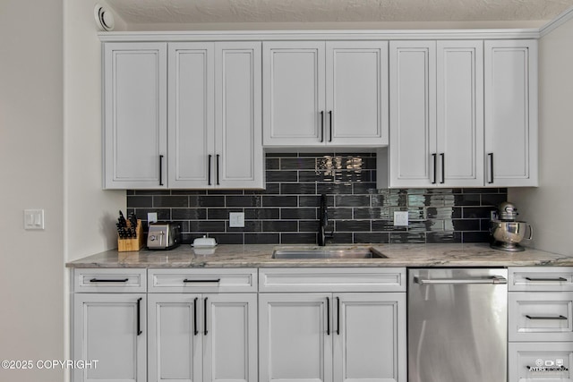 kitchen with backsplash, dishwasher, white cabinets, and a sink