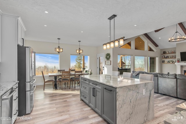 kitchen featuring gray cabinetry, open floor plan, stainless steel appliances, light wood-style floors, and a textured ceiling