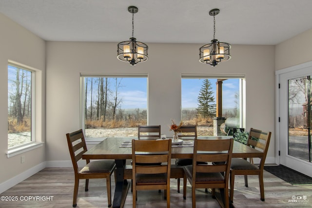 dining space with a notable chandelier, light wood-style flooring, and baseboards