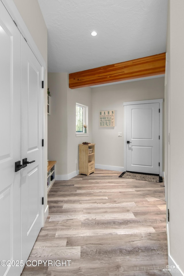 interior space featuring recessed lighting, beamed ceiling, baseboards, and light wood finished floors