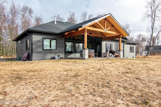 rear view of property featuring roof with shingles and a patio area