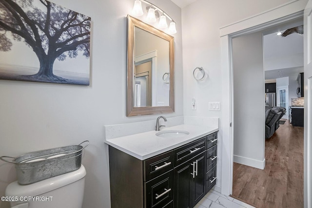 bathroom featuring toilet, vanity, and baseboards