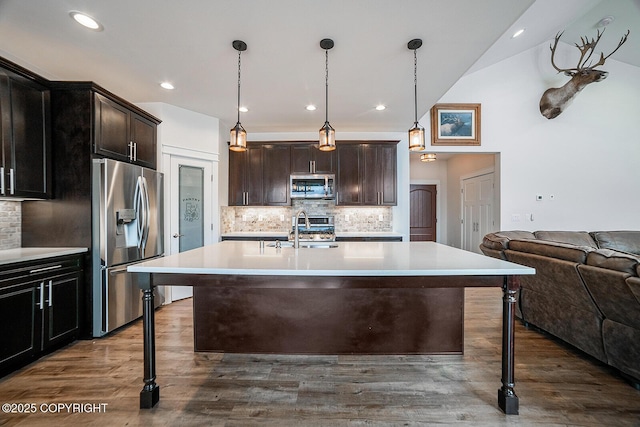 kitchen with dark wood finished floors, open floor plan, a breakfast bar area, light countertops, and stainless steel appliances