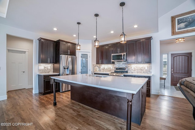 kitchen with a sink, dark wood-type flooring, light countertops, dark brown cabinets, and appliances with stainless steel finishes