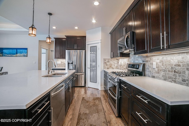 kitchen with a sink, light countertops, light wood-style floors, appliances with stainless steel finishes, and tasteful backsplash