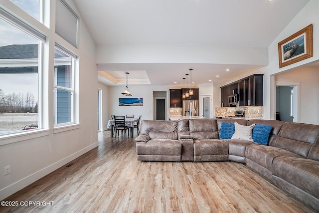 living area with baseboards, light wood-type flooring, and a wealth of natural light