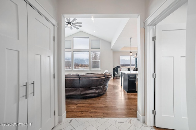 hallway with light wood finished floors and vaulted ceiling