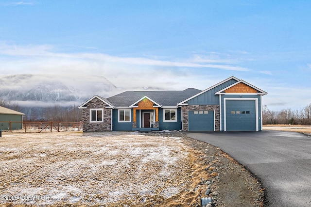 view of front of house featuring driveway, stone siding, fence, board and batten siding, and a garage