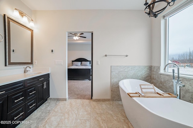 bathroom featuring a ceiling fan, a soaking tub, ensuite bath, and vanity