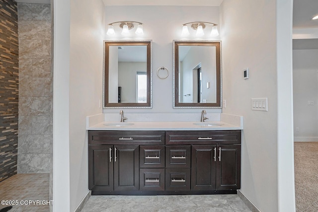 full bathroom featuring a sink, tiled shower, baseboards, and double vanity