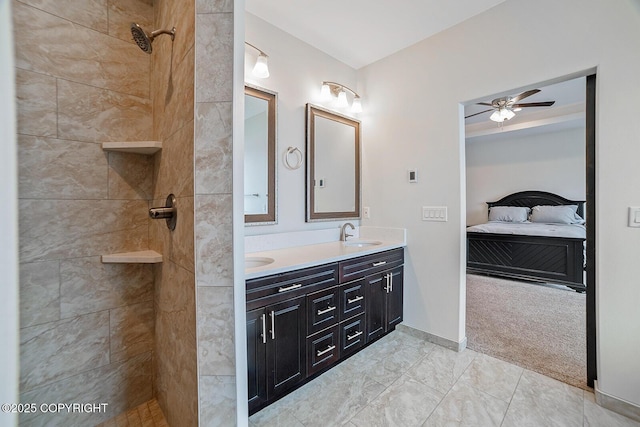 bathroom featuring double vanity, a tile shower, ceiling fan, a sink, and ensuite bathroom