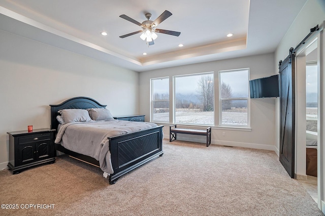 bedroom featuring a tray ceiling, recessed lighting, a barn door, baseboards, and light colored carpet