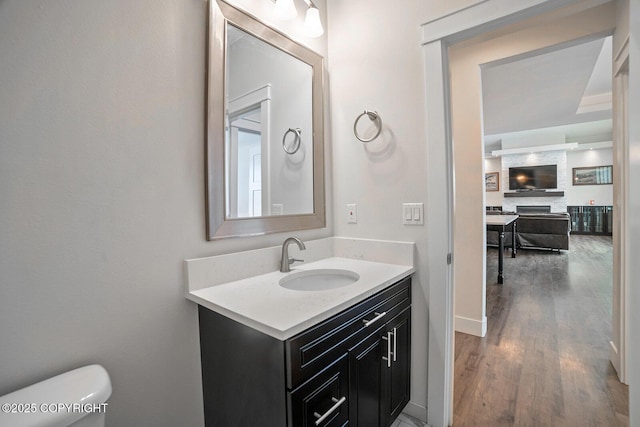 half bathroom with baseboards, toilet, wood finished floors, and vanity