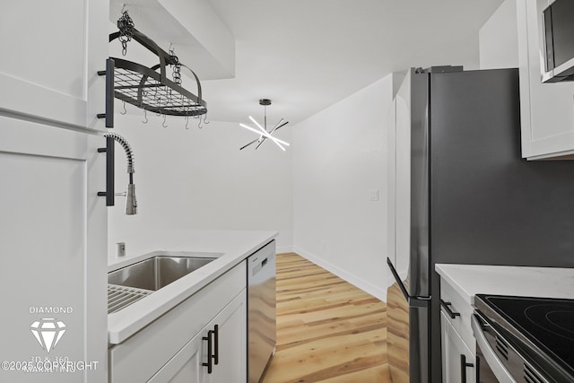 kitchen featuring light wood-type flooring, stainless steel appliances, a chandelier, and light countertops