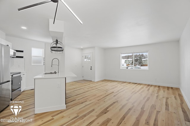 kitchen with a sink, white cabinets, electric range oven, and light countertops