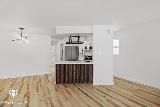 kitchen featuring backsplash, white cabinetry, appliances with stainless steel finishes, an inviting chandelier, and light countertops