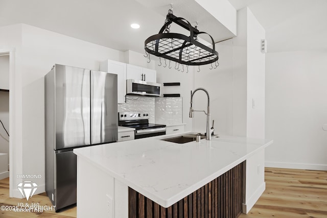 kitchen featuring light wood-style flooring, light stone counters, recessed lighting, stainless steel appliances, and decorative backsplash