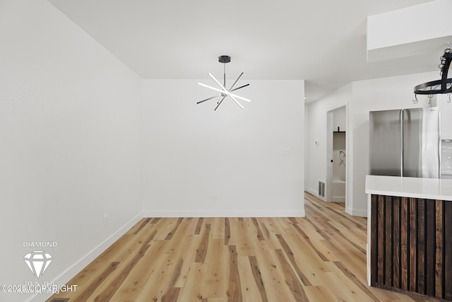 unfurnished dining area featuring light wood-style floors, baseboards, a notable chandelier, and a skylight