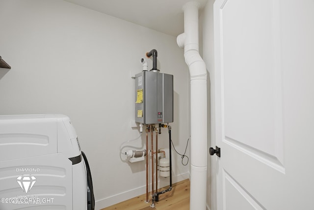 laundry area featuring light wood-type flooring, water heater, separate washer and dryer, baseboards, and laundry area