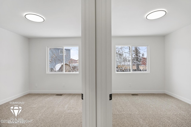 carpeted spare room featuring visible vents and baseboards