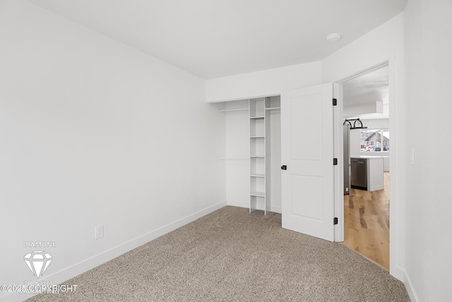 unfurnished bedroom with a closet, light colored carpet, and baseboards