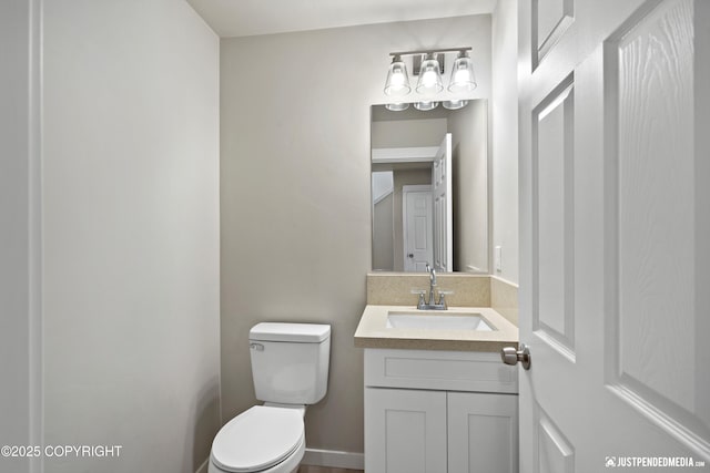 bathroom featuring toilet, vanity, and baseboards