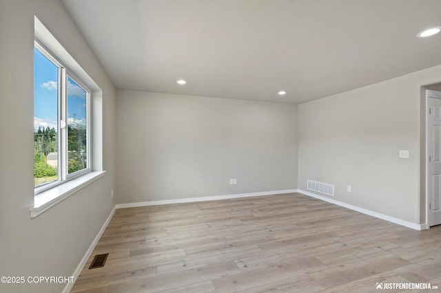 empty room featuring visible vents, baseboards, and light wood-style floors