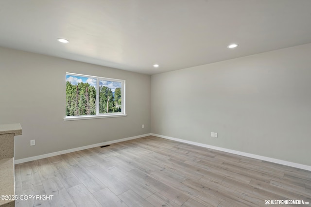 empty room featuring recessed lighting, light wood-type flooring, and baseboards