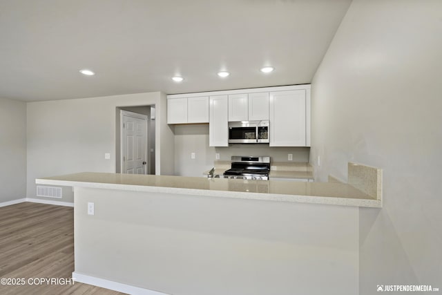 kitchen featuring visible vents, wood finished floors, white cabinetry, recessed lighting, and stainless steel appliances