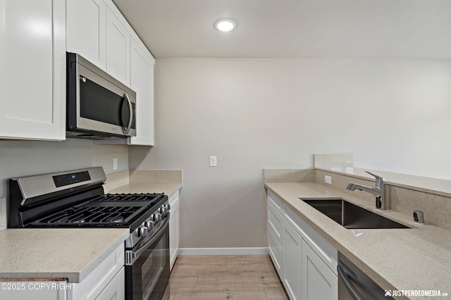 kitchen featuring white cabinetry, stainless steel appliances, light wood-type flooring, and a sink