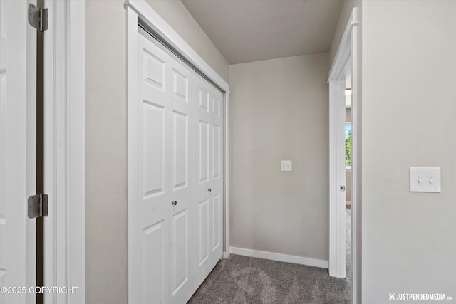 hall featuring baseboards and dark colored carpet