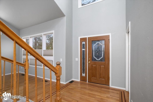 foyer entrance featuring stairway, baseboards, and wood finished floors