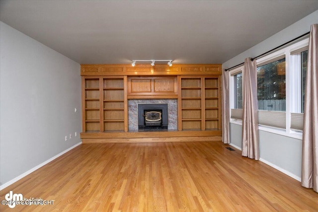 unfurnished living room featuring visible vents, baseboards, light wood-style flooring, and rail lighting