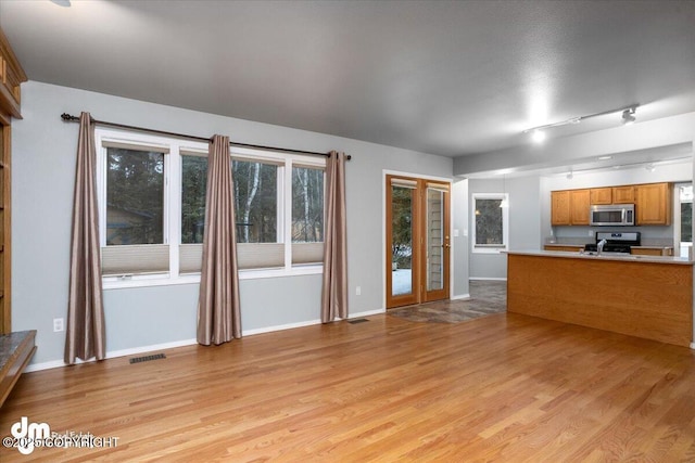 unfurnished living room featuring light wood-style flooring, baseboards, and visible vents