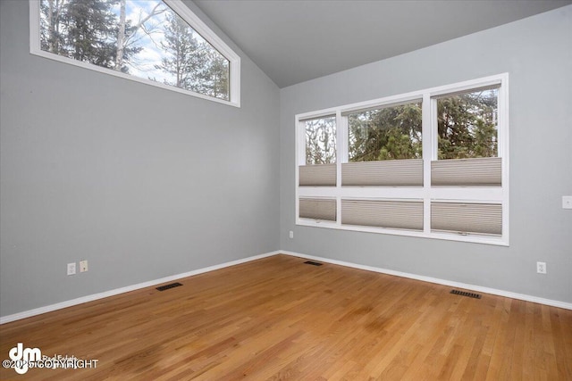 empty room featuring light wood finished floors, visible vents, and baseboards