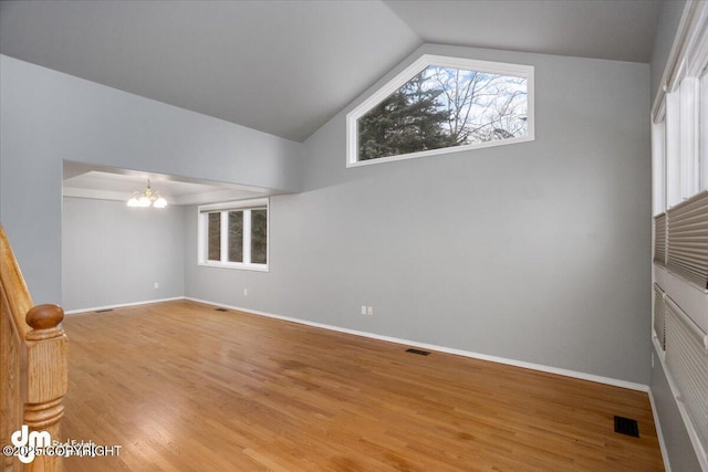 empty room with light wood-type flooring, visible vents, baseboards, and a chandelier