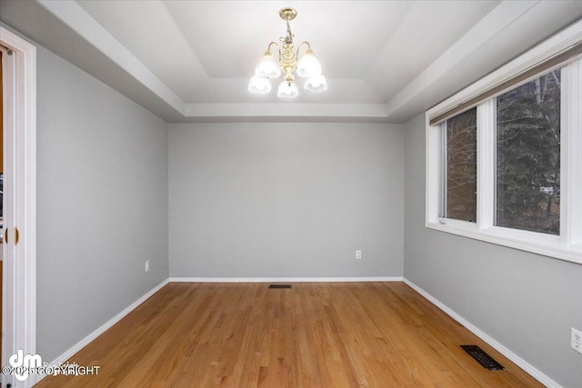 unfurnished room featuring a chandelier, visible vents, a raised ceiling, and baseboards