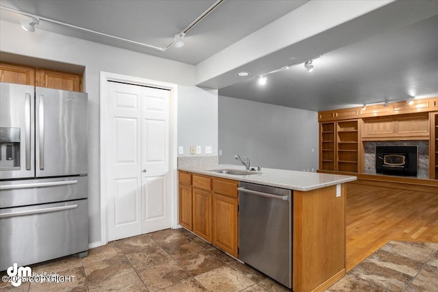 kitchen with a peninsula, rail lighting, appliances with stainless steel finishes, and a sink